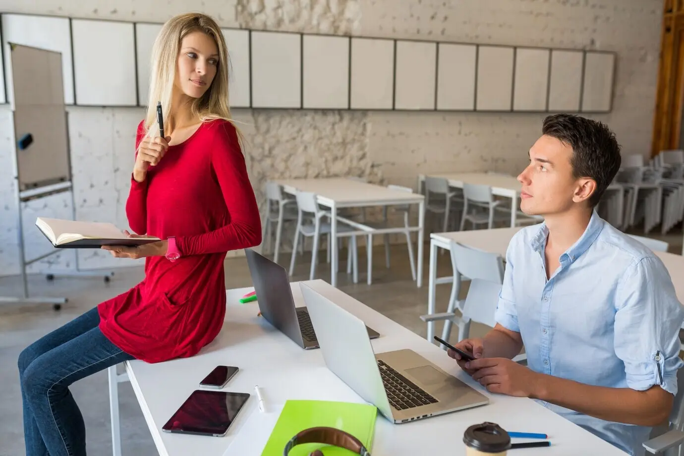 Attractive young people collaborating online in an open-plan coworking office room.